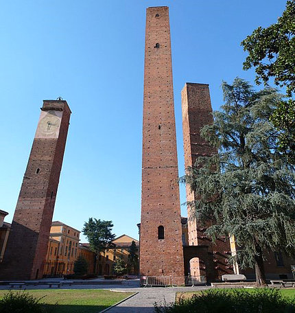 Three brick towers stand against blue sky on the University of Pavia's campus in Italy