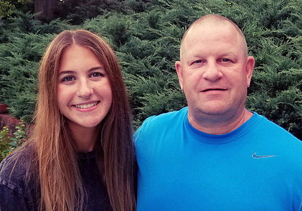 Teen girl with her father smiling into camera