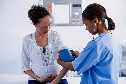 Nurse examines pregnant woman.