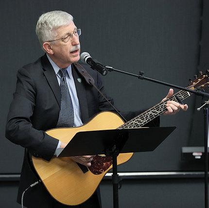 Collins holds guitar, sings into microphone