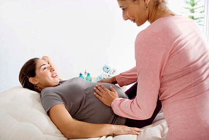 A woman touches a pregnant women's stomach