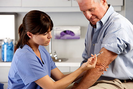 A nurse gives an older adult a vaccine in the arm