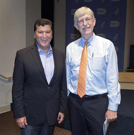 Collins and Zerhouni, both smiling, pose for a photo in front of the blue NIH backdrop.