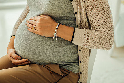 Pregnant woman torso with hand on baby bump