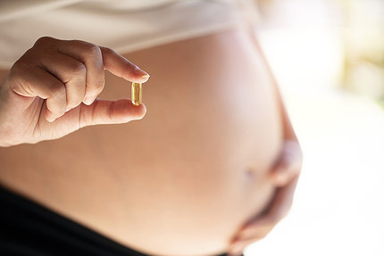 A pregnant woman holds a dietary supplement pill