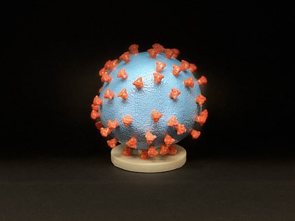 A blue ball with protruding orange spikes sits on a wooden base.