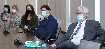 Animal care workers, in masks, seated at conference table, looking at screen.