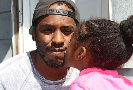 Black man in cap is kissed by young girl