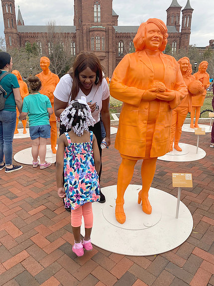  Alongside her statue in front of the Smithsonian castle, Jones bends down to chat with a young girl of color.