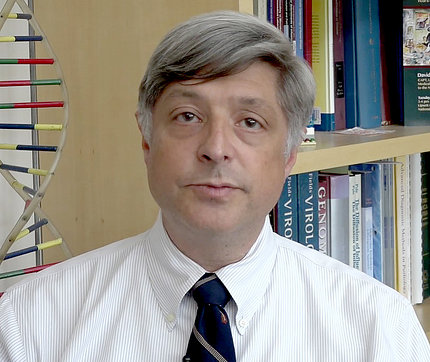 Dr. Jeffery Taubenberger in front of colorful double helix and bookshelf