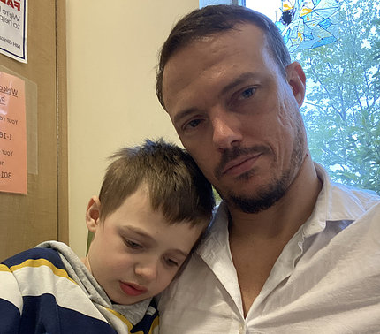 Hampus Flysjo, age 8, rests his head on his father's shoulder at a room in the Clinical Center