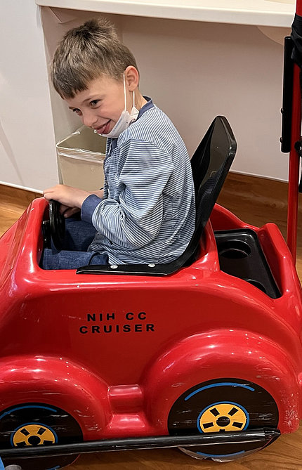 A smiling Hampus sits in a red NIH CC Cruiser with his hand on the wheel