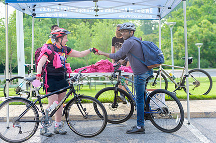 2 cyclists fistbump in greeting, amid several bikes