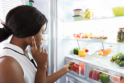 A woman looks in a refrigerator crisper