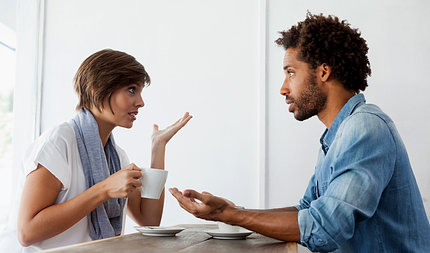 Woman holding mug and gesturing toward a man