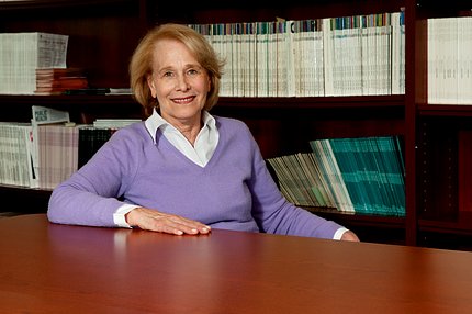 Dr. Rena Wing, seated at table with bookshelves behind her