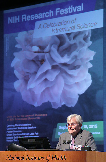 Gottesman at NIH podium with 2015 festival slide projected on screen behind him.
