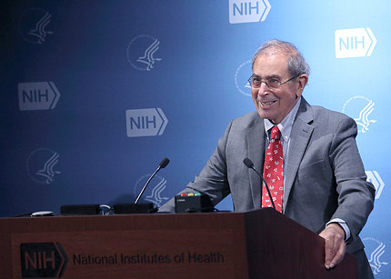 Gallin at podium with NIH logo backdrop behind him