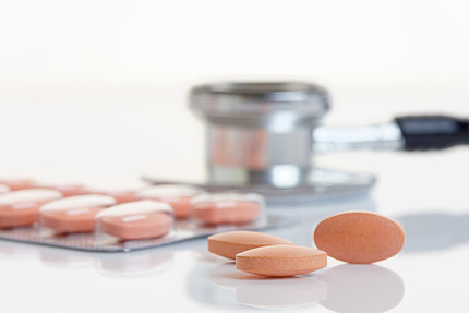 Loose tablets on a white table, with a sealed pack of tablets in the background.