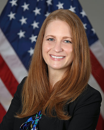 Dr. Tara Schwetz smiles in front of American flag