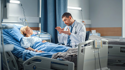 Stock image of female in hospital bed with male in labcoat talking to her