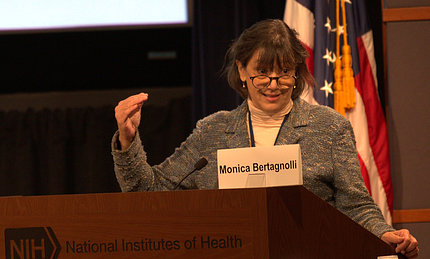 Bertagnolli speaks from behind a podium. The picture is taken mid-gesture.