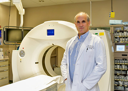Wood, in white labcoat, stands in front of MRI machine