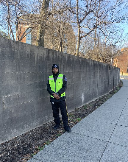 Crutchfield poses next to a tall concrete wall. He wears a black beanie and fluorescent green vest. 