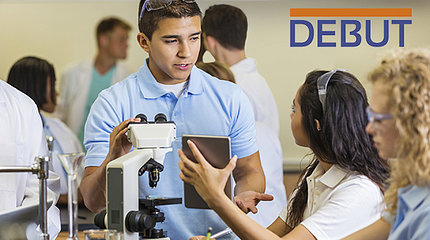 Students hold a discussion over a microscope. "DEBUT" is written in dark blue letters in the upper right corner, with an orange line running parallel to and above the letters.