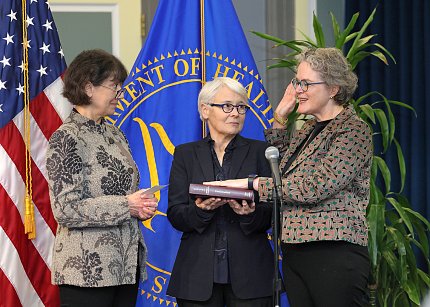 Marrazzo, right, speaks the oath with her right hand upraised and her left on a book (held by her spouse, Hofmann). At left, Bertagnolli reads from a notecard.