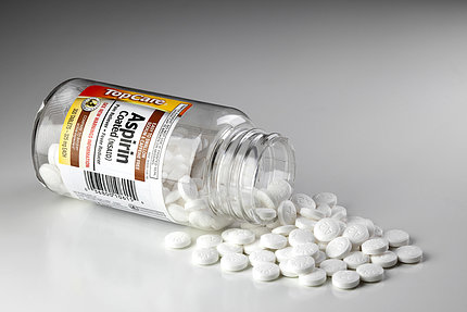 Bottle of aspirin tablets spilling onto surface