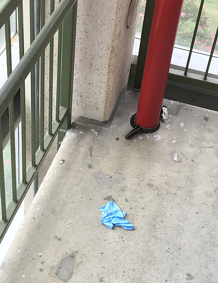 Blue disposable gloves are left on the ground near a parking garage.