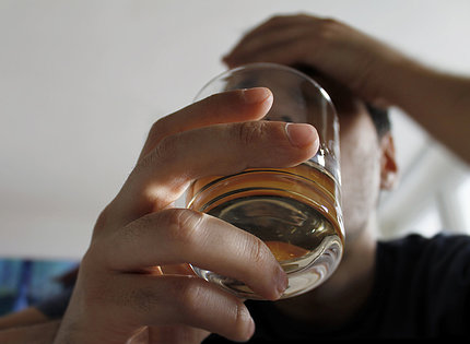 Close up of cocktail held by man with other hand holding his forehead