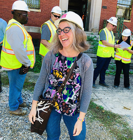 Dr. Sarah Leavitt wearing a hard hat stands on a construction site.