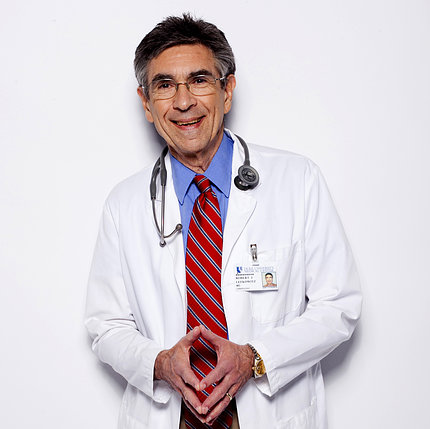 Dr. Robert Lefkowitz stands with fingertips pressed together, wearing white lab coat