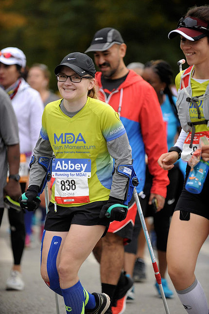 Hauser, smiling, wearing forearm crutches, running in a marathon