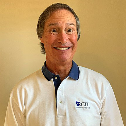 McLean smiling against a light yellow backdrop. He wears a white polo shirt with a CIT logo on the chest.