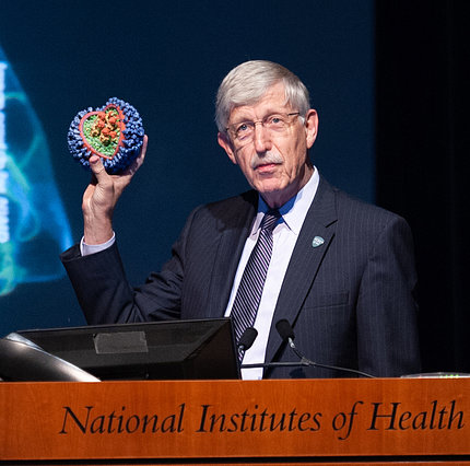 Collins holds up a 3-D model of the flu virus