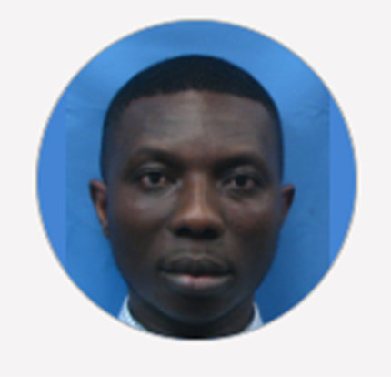 Addae looks into the camera for his ID badge photo. The top of his white shirt collar is visible and the background behind him is blue.