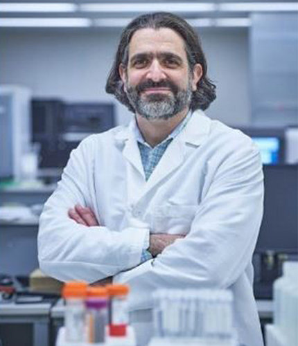 Dr. Adam Resnick in white lab coat, arms folded, standing in a lab