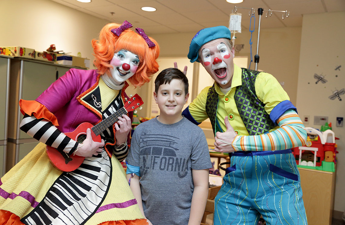 Young patient mugs with two clowns.