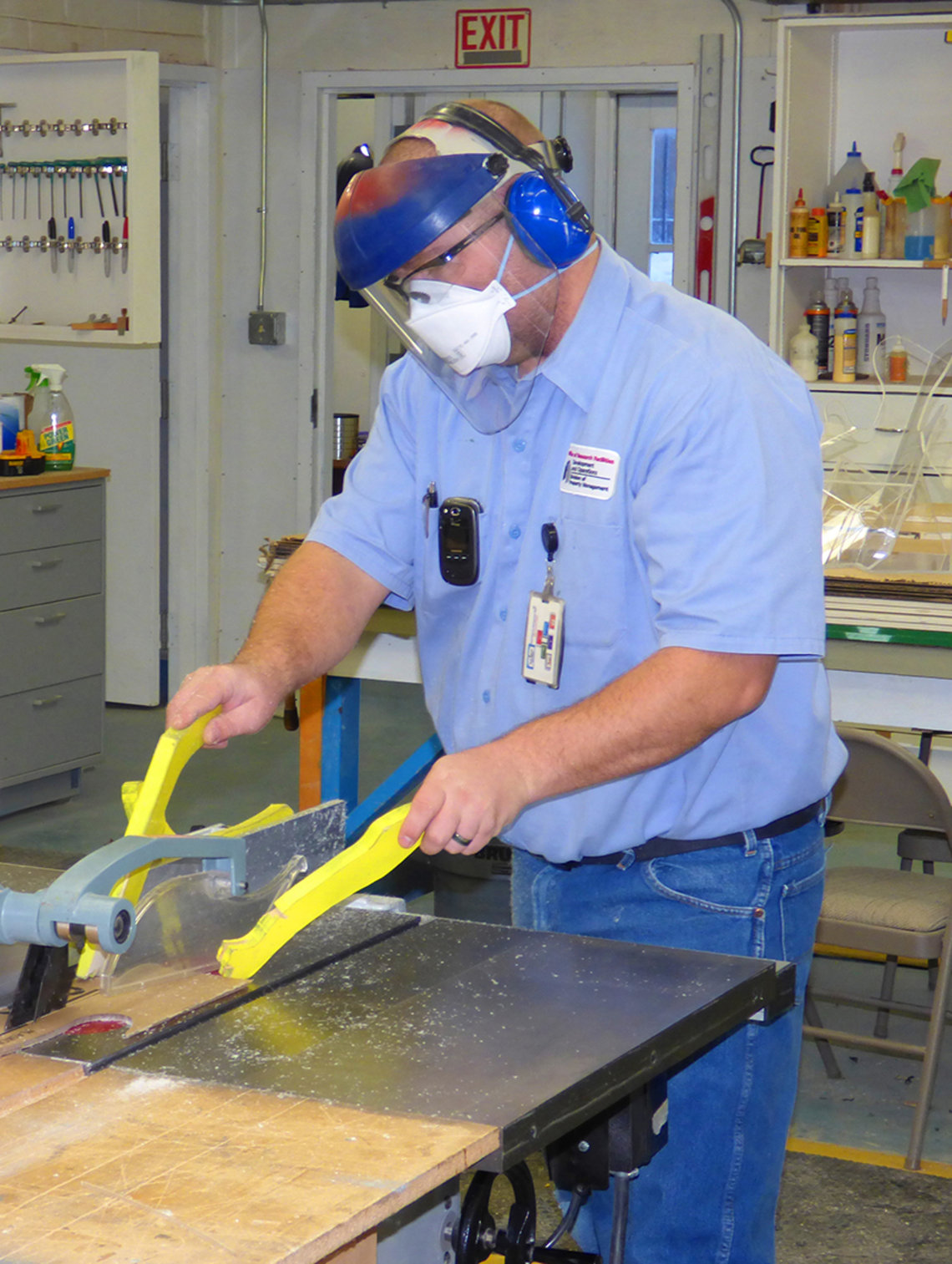Uniformed man wearing safety goggles and working with saw 
