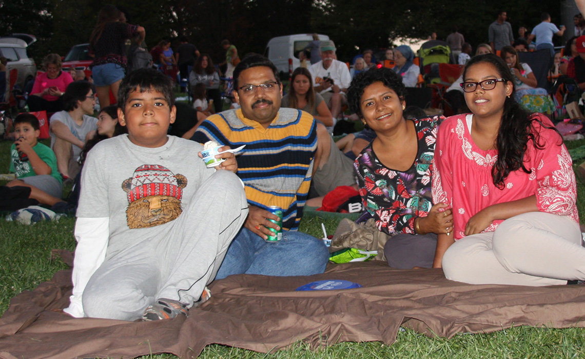 A group of movie-goers sit on the lawn outside the Strathmore.