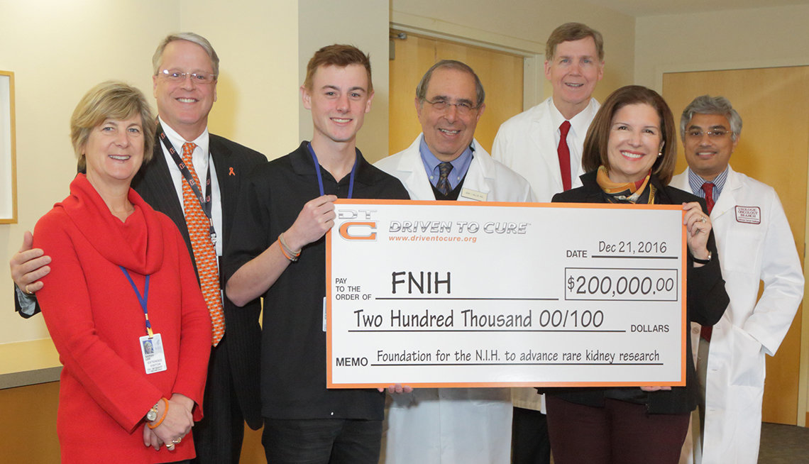 Andrew Lee holds $200,000 check that he presents to the Foundation for the NIH. He is surrounded by his parents and NIH doctors.