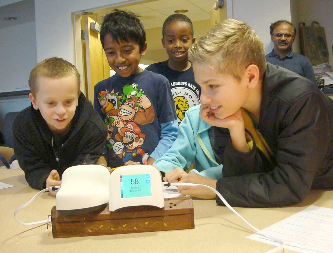 Four young boys crowd around a science project