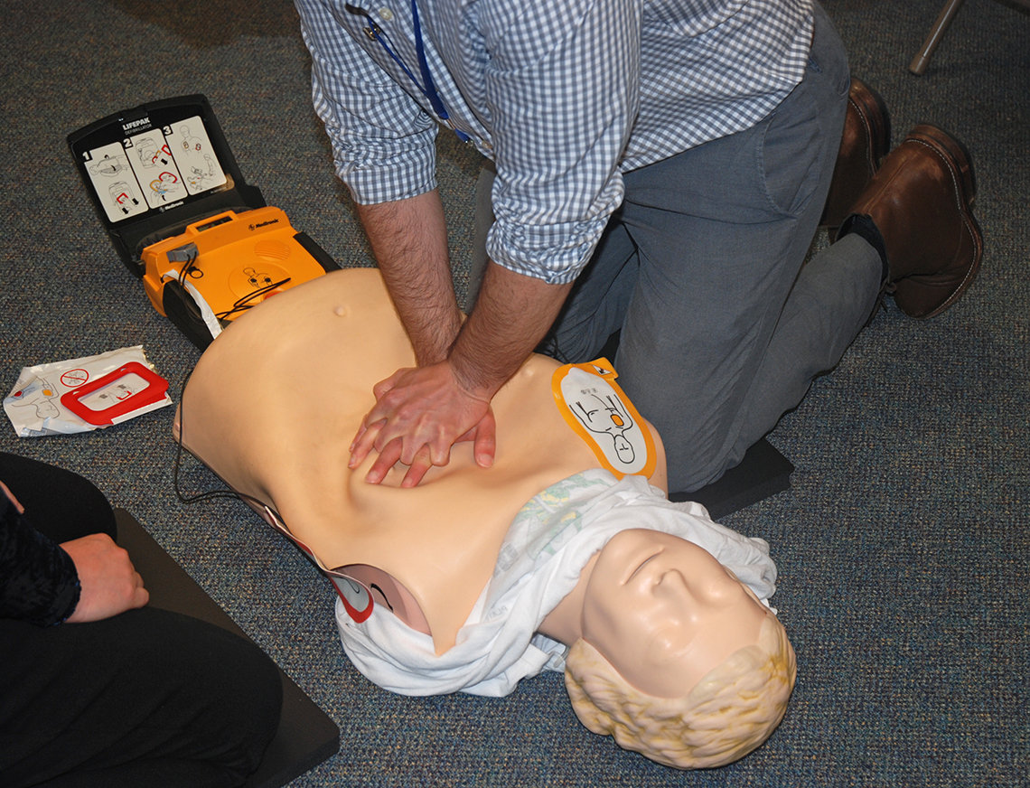 Trainees practice AED use on mannequins.