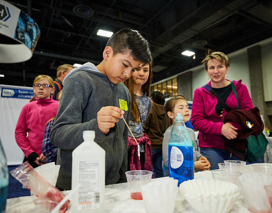 A student at the NHGRI booth admires large strands of extracted strawberry DNA.