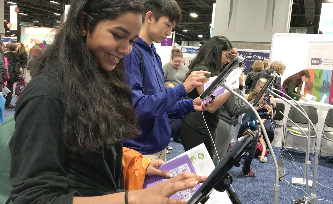 Visitors to the NIBIB booth play an iPad game “Want to be a bioengineer?”