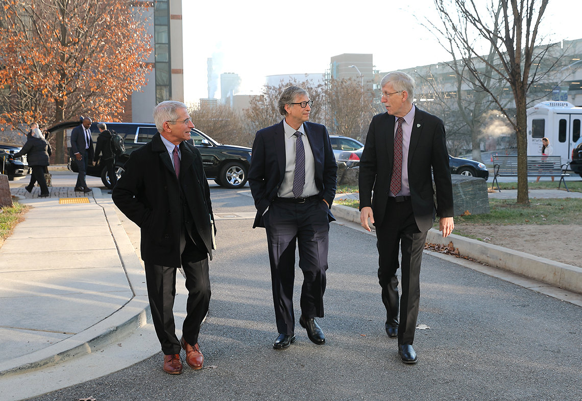 Bill Gates walks outdoors with Drs. Collins and Fauci.