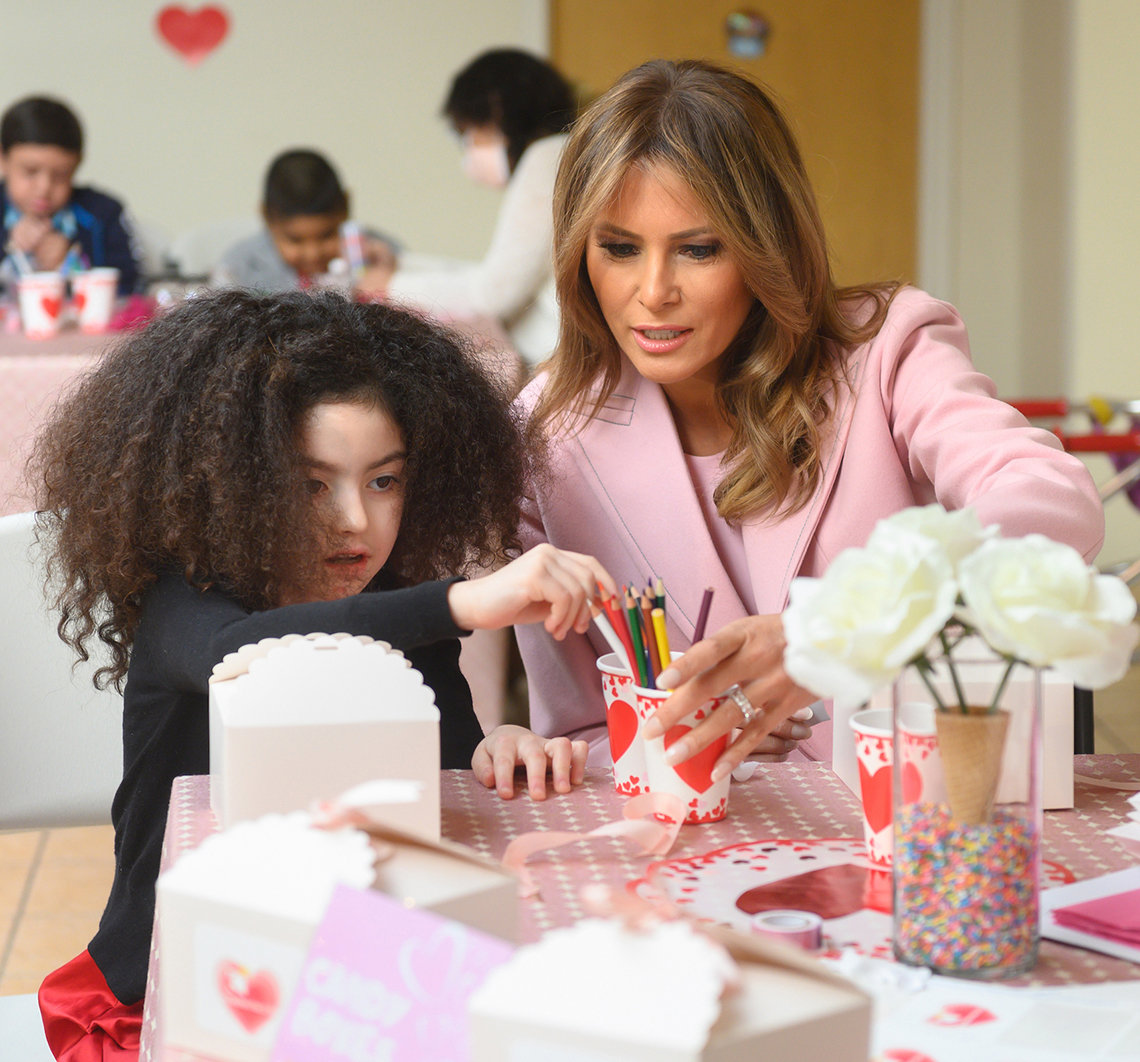 Little girl and First Lady Trump handle colored pencils at craft table.